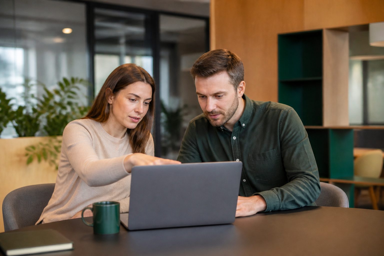 Dwie osoby omawiają aplikację wewnętrzną na ekranie laptopa